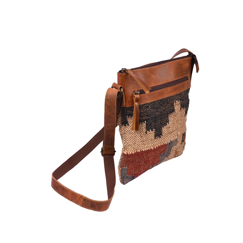 May include: A brown leather crossbody bag with a woven tapestry-style front panel in shades of beige, red, blue, and black. The bag has a zipper closure and a long adjustable strap.