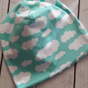 Könnte beinhalten: Eine türkisblaue Mütze mit einem weißen Wolkenmuster.