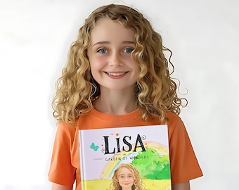 May include: A young person with curly blonde hair smiles while holding a book titled "Lisa in Garden of Wonders." The book cover features an illustration of a girl with curly hair, a rainbow, and a garden scene. The person is wearing an orange t-shirt.