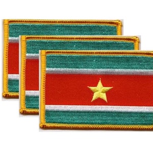 May include: Three embroidered patches featuring the flag of Suriname. Each patch has a red field with a yellow star, a green stripe at the top and bottom, and a white stripe in the middle. The patches are rectangular with a gold border.