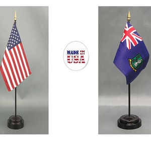 May include: Two small flags on stands. The flag on the left is the American flag, with red and white stripes and blue field with white stars. The flag on the right is a blue flag with a Union Jack and a crest. The flags are on black stands.