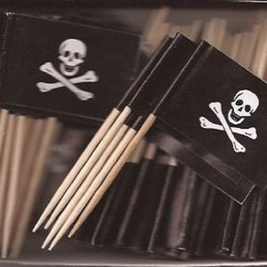 May include: A collection of pirate-themed toothpick flags. Each flag is black with a white skull and crossbones design. The flags are attached to wooden toothpicks, creating a fun and thematic party supply.