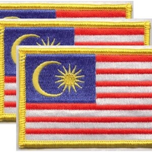 May include: Three embroidered patches featuring the flag of Malaysia. Each patch has a blue canton with a yellow crescent and star, alternating red and white stripes, and a yellow border. The patches are rectangular and have a stitched appearance.