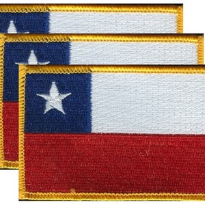 May include: Three embroidered patches featuring the flag of Chile. Each rectangular patch has a blue square with a white star in the upper left corner, a white stripe, and a red stripe. The patches are outlined with gold thread.