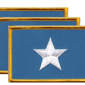 May include: Three rectangular blue patches with a white star in the center. Each patch has a gold border. The patches are arranged in a slightly overlapping pattern.