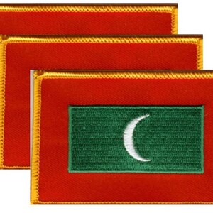 May include: Three rectangular patches featuring the flag of the Maldives. Each patch has a red background with a gold border. A green rectangle with a white crescent moon is centered on the red field. Patches are likely for clothing or accessories.