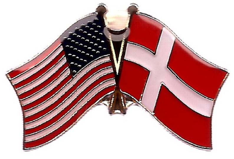 K&ouml;nnte beinhalten: Eine Anstecknadel mit den Flaggen der Vereinigten Staaten und D&auml;nemarks. Die amerikanische Flagge ist rot, wei&szlig; und blau mit Sternen und Streifen. Die d&auml;nische Flagge ist wei&szlig; auf rotem Grund. Die Flaggen sind nebeneinander.