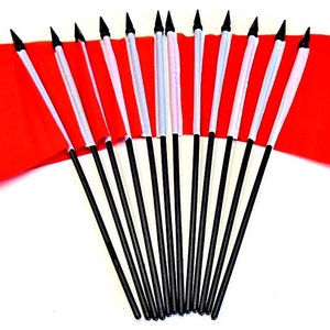 May include: A collection of small Moroccan flags. Each flag is red with a green star in the center and is attached to a black pole with a white top. The flags are arranged in a fan shape.