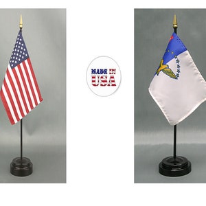 May include: Two small flags on black stands. The flag on the left is the American flag with red and white stripes and blue stars. The flag on the right is white with a blue top and a gold emblem. A circular "Made in USA" logo is in the center.