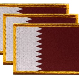May include: Three rectangular embroidered patches featuring the Qatar flag. Each patch has a maroon field with a white serrated edge on the left side. The patches are bordered with gold thread.