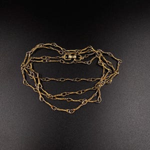 May include: A gold chain necklace with a twisted rope design. The chain is layered and has a clasp closure.
