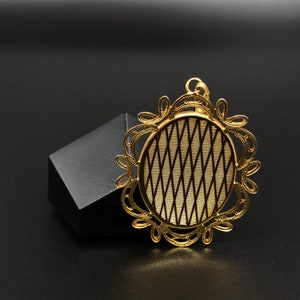 May include: A gold-toned pendant with a circular, intricate design. The pendant features a delicate, woven pattern within the circle.