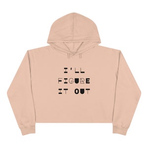 May include: A cropped, light pink hoodie with a black graphic that reads "I'LL FIGURE IT OUT".