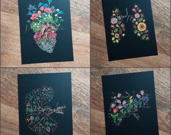 May include: Four black art prints featuring floral designs within anatomical shapes. One print shows a heart, another lungs, a kidney, and a fourth print with a floral design. Each print has the artist's signature.