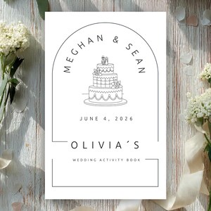 May include: A white rectangular wedding activity book cover featuring a black line art illustration of a three-tiered cake with a couple topper inside an arch. The text reads MEGHAN & SEAN, JUNE 4, 2026, OLIVIA'S, and WEDDING ACTIVITY BOOK.
