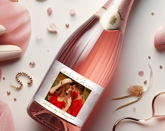 May include: A pink champagne bottle with a white label featuring a photo of a couple and the text "Grabus & Sean Valentine's Day Party 2023".