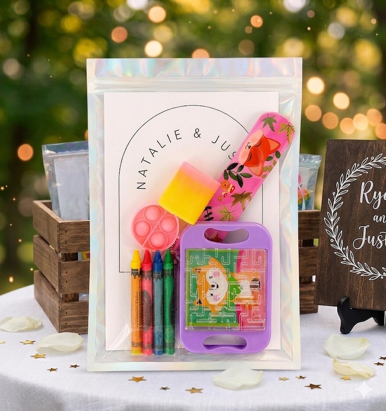 May include: A clear iridescent pouch containing a white card with the text NATALIE & JUSTIN, a pink fox-patterned ruler, a yellow and pink rectangular eraser, a small pink circular fidget toy, four crayons, and a purple handheld maze game.