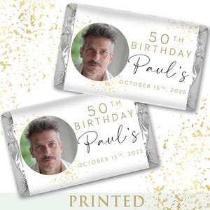 May include: Two personalized candy bar wrappers with a photo of a man, gold text, and the words "50th Birthday Paul's October 15th, 2025". The wrappers are silver and have a gold confetti design.
