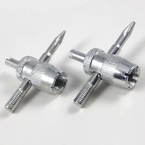 May include: Two silver metal tire valve stem tools. Each tool has a knurled center, a threaded end, a slotted end, and a pointed end. The tools are designed for tire maintenance and repair.