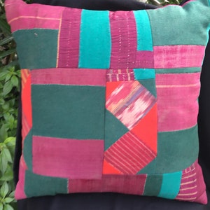 Könnte beinhalten: Ein Patchwork-Kissen mit verschiedenen Farben und Texturen, darunter Grün, Rot, Pink und Blau. Das Kissen ist aus verschiedenen Stoffen gefertigt, einige davon mit einem gestreiften Muster.
