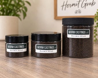 May include: Three clear cylindrical plastic jars of varying sizes filled with dark brown worm castings. Each jar features a black screw-top lid and a white label with black text reading WORM CASTINGS and Hermit Grub with a small crab icon.