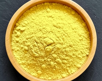 May include: A round, light-colored wooden bowl filled with a fine, bright yellow powder. The texture of the powder appears granular and dry, evenly distributed within the circular container, showcasing a vibrant, uniform yellow color throughout.