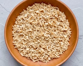 May include: A round, terracotta-colored ceramic bowl filled with a generous portion of dried, shredded, light beige food strands. The bowl has a smooth, matte finish and a simple, circular design, containing a heap of thin, textured, dried ingredients.