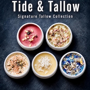 May include: Five round metal tins containing Tide & Tallow Signature Tallow Collection balms. The balms feature varied textures and inclusions, including red with pine nuts, white with dried herbs, pink with salt, plain yellow, and blue with flower petals.