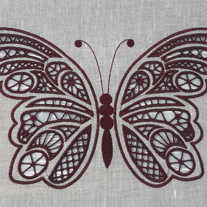 May include: An embroidered butterfly in burgundy thread on a light grey fabric. The butterfly's wings display detailed patterns and cut-out sections. The image highlights the delicate craftsmanship of the embroidery.
