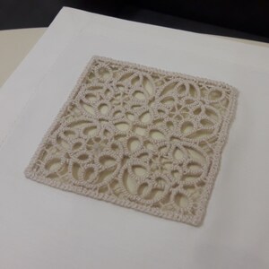 May include: A square piece of beige crochet lace with a delicate floral pattern.