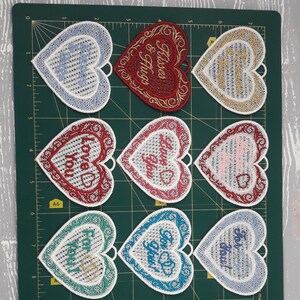 Pode incluir: Nove ornamentos brancos em forma de cora&ccedil;&atilde;o com desenhos e texto bordados. O texto nos ornamentos inclui "Love You", "Forever & Always", "For You", "Love You", "Love You", "For You", "For You", "For You" e "For You".