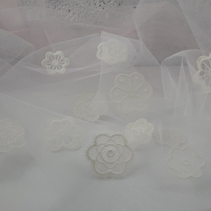 May include: White tulle fabric with delicate white lace flowers and cloud shapes.