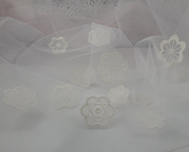May include: White tulle fabric with delicate white lace flowers and cloud shapes.