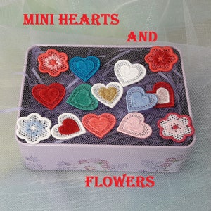 May include: A tin box filled with small embroidered hearts and flowers. The hearts are in various colors, including red, blue, green, and white. The flowers are white with a red center. The box is labeled "MINI HEARTS AND FLOWERS".