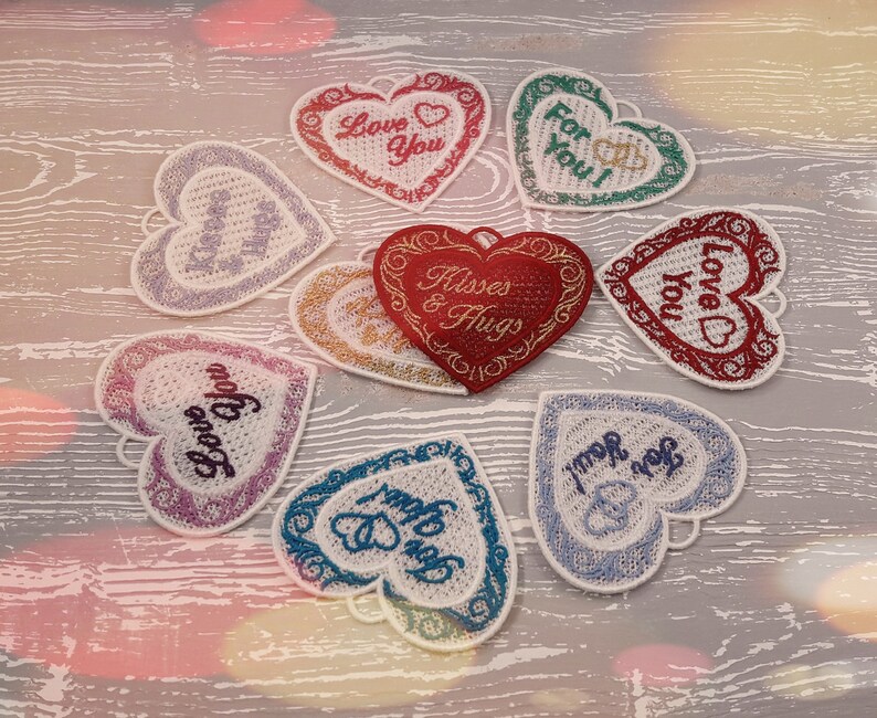 Pode incluir: Oito enfeites de cora&ccedil;&atilde;o de feltro bordados com diferentes mensagens sobre o amor, incluindo "Love You", "Kisses & Hugs" e "For You!" Os cora&ccedil;&otilde;es s&atilde;o de v&aacute;rias cores, incluindo vermelho, rosa, azul e verde.