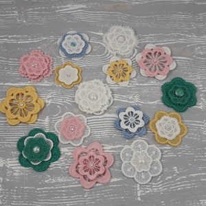 May include: Assortment of 13 white, pink, blue, green and yellow lace flower embellishments with pearl centers.