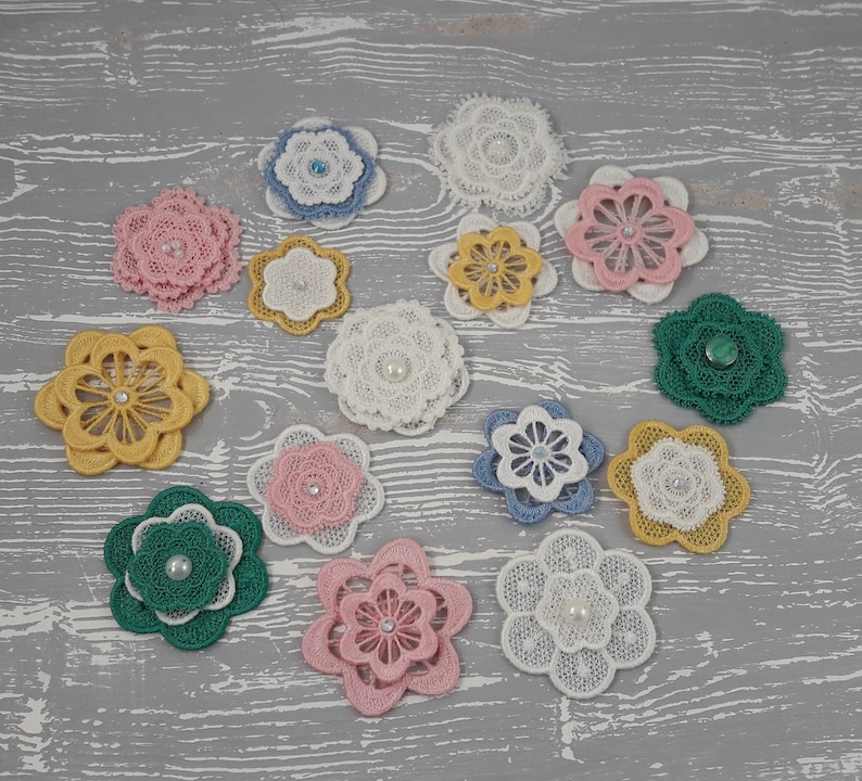 May include: Assortment of 13 white, pink, blue, green and yellow lace flower embellishments with pearl centers.
