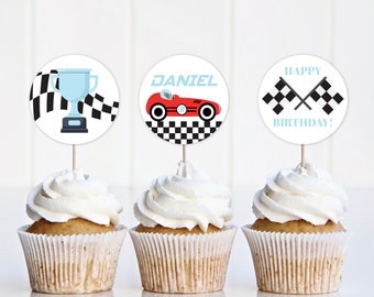 May include: Three cupcakes decorated with round toppers featuring a checkered flag design. One topper has a trophy, another has a red race car with the name "DANIEL" and the last one says "HAPPY BIRTHDAY!"