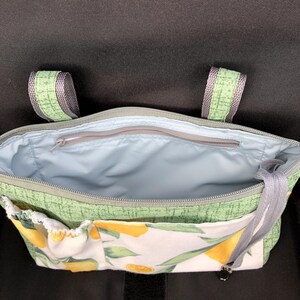 Op de afbeelding: Een groene stoffen tas met een citroenprint op het voorvak en een lichtblauwe voering. De tas is voorzien van een ritssluiting aan de bovenkant, twee groene stoffen hengsels aan de bovenzijde en een extra ritsvak in het hoofdvak.