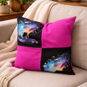 May include: Square decorative pillow with a patchwork design. Two black squares feature a watercolor wolf silhouette against a starry sky. The other two squares are bright pink. The pillow is on a beige sofa.