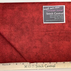 May include: Red fabric with a black honeycomb pattern. The fabric is folded in half and a business card is visible with the text "visit our new forever home! Stitch Central 128 E Glenside Ave Glenside, PA 19038 267-277-4148 www.mystitchcentral.com". A ruler is visible at the bottom of the image with the text "Stitch Central".