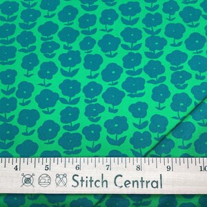 May include: Green fabric with a repeating pattern of teal-colored stylized flowers. A wooden ruler with the text "Stitch Central" is at the bottom of the image, measuring up to 11 inches.