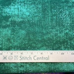 Może przedstawiać: Zbliżenie na tkaninę w kolorze turkusowym z fakturą w kropki. Na tkaninie leży drewniana linijka z napisem "Stitch Central".
