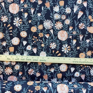 May include: Dark navy fabric with a floral pattern featuring peach and white flowers, green leaves, and stems. A wooden ruler with the text "No, I will not hem your pants" is across the bottom. The website address www.mystitchcentral.com is also visible.