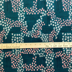 May include: Teal fabric with a repeating pattern of pink and light blue dots and dark teal rectangles and lines. The text "No, I will not hem your pants" is visible. A ruler is placed across the fabric.