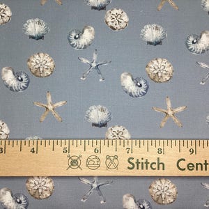 May include: Light blue fabric with a repeating pattern of seashells and starfish. The fabric has a ruler with the text "Stitch Central" printed on it. The ruler measures up to 10 inches.