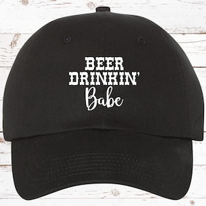 May include: Black baseball cap with white embroidered text that reads "Beer Drinkin' Babe".
