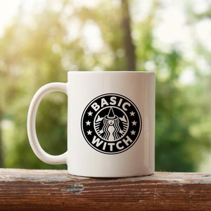 May include: White ceramic mug with a black and white graphic of a witch with a star-shaped crown and the text "BASIC WITCH" in a circle.
