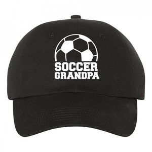 May include: Black baseball cap with a white soccer ball graphic and the text "Soccer Grandpa" embroidered on the front.