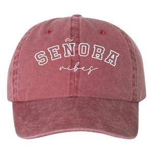 Op de afbeelding: Een rode baseballcap in vintage stijl met witte geborduurde tekst die "SENORA vibes" luidt.